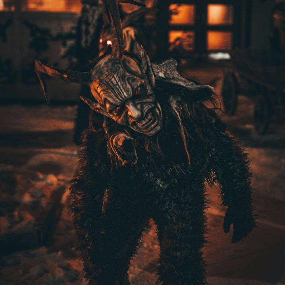 Traditionelle Krampusfigur in festlicher, winterlicher Atmosphäre bei Nacht.