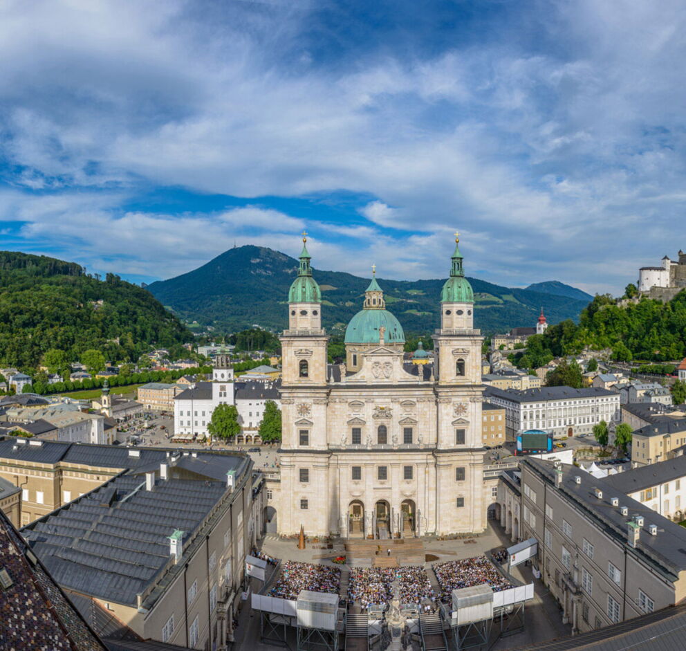 Luftaufnahme von Salzburg mit Dom und Festung Hohensalzburg unter klarem Himmel.