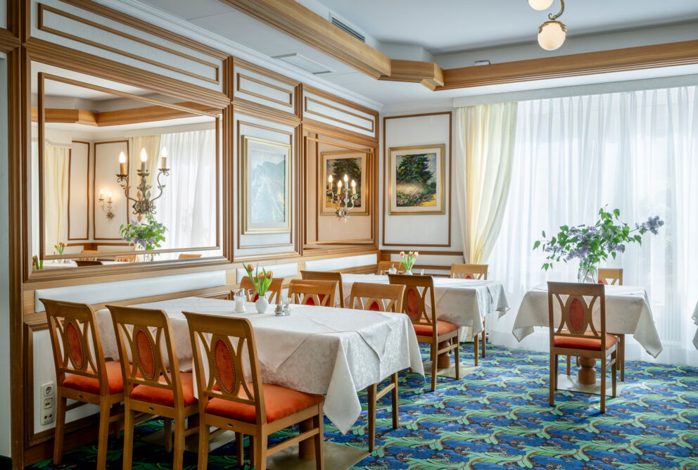 Bright and elegantly furnished dining tables with white tablecloths and flower arrangements.