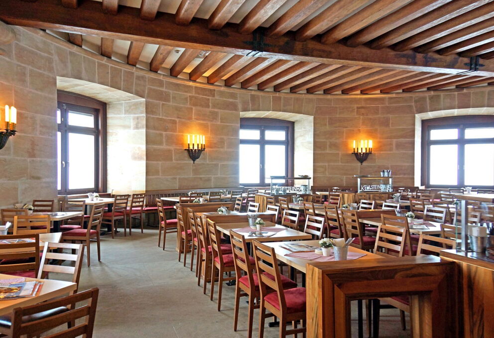 Gemütliches Restaurant mit Holzmöbeln und Kerzenleuchtern in traditioneller Architektur.