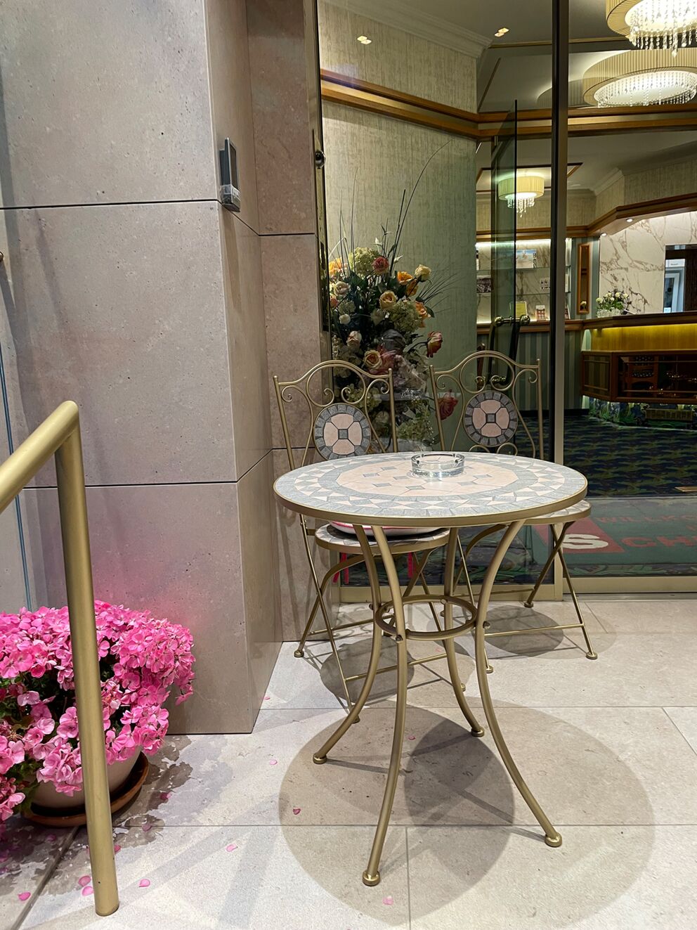 Kleiner Tisch mit Stühlen und Blumenarrangement vor einer Spiegelwand