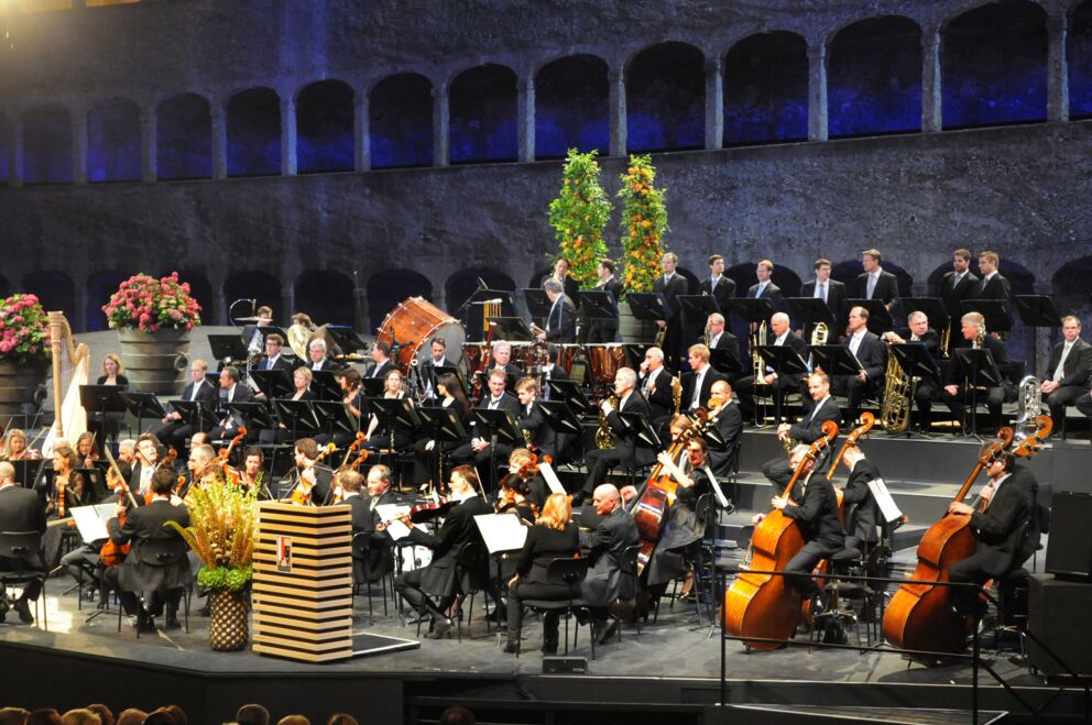 Orchester spielt in historischer Kulisse, Musiker in eleganter Formation.
