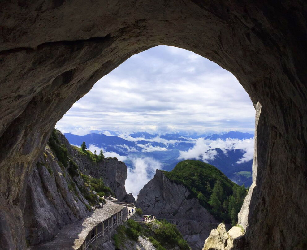 View through a cave to impressive mountains and clouds in Salzburger Land.