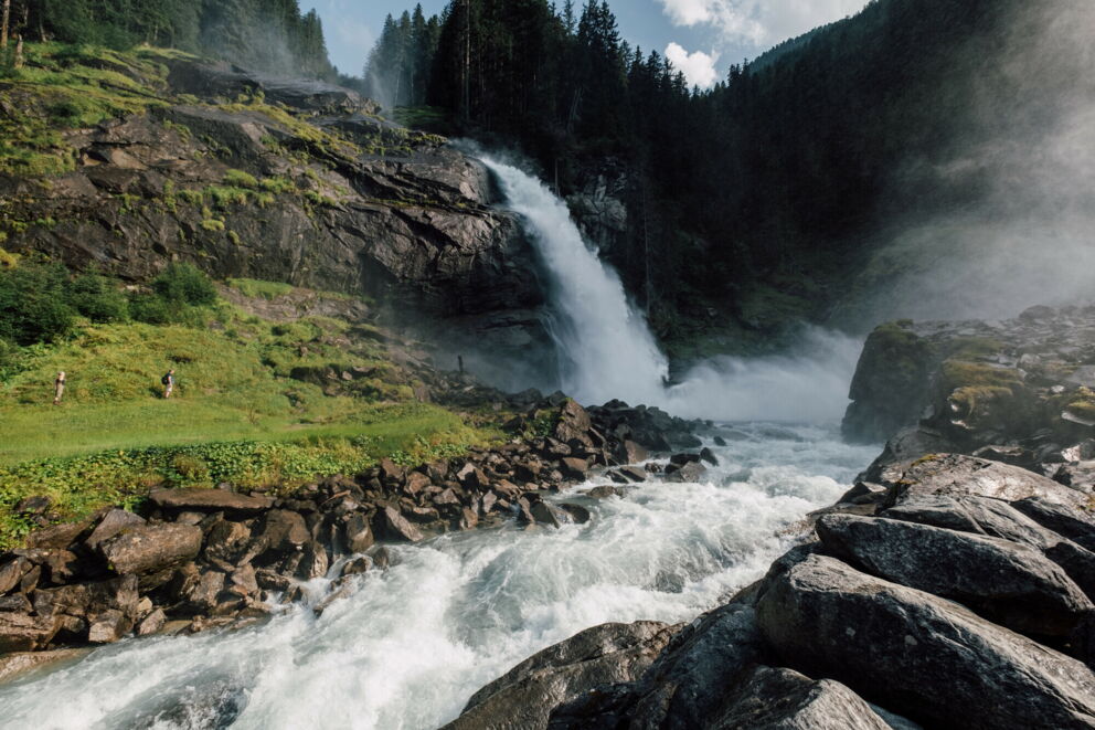 Tosender Wasserfall inmitten üppiger, grüner Landschaft und dichter Wälder.