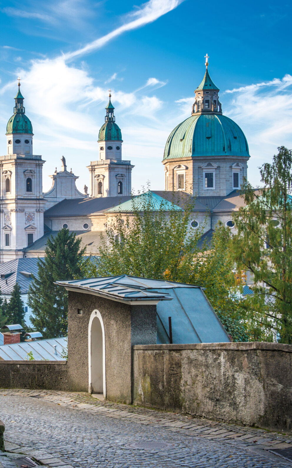 Blick auf Salzburgs historische Türme und Gebäude, von einem erhöhten Gartenweg aus.