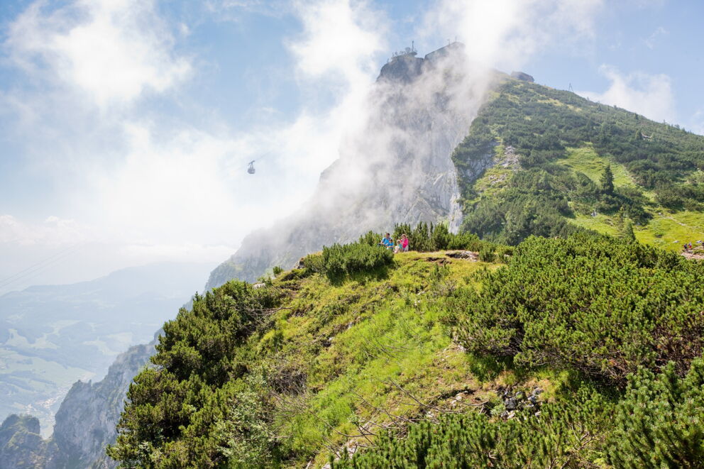 Seilbahn schwebt vor beeindruckendem Bergpanorama in klarer, sonniger Alpenlandschaft.