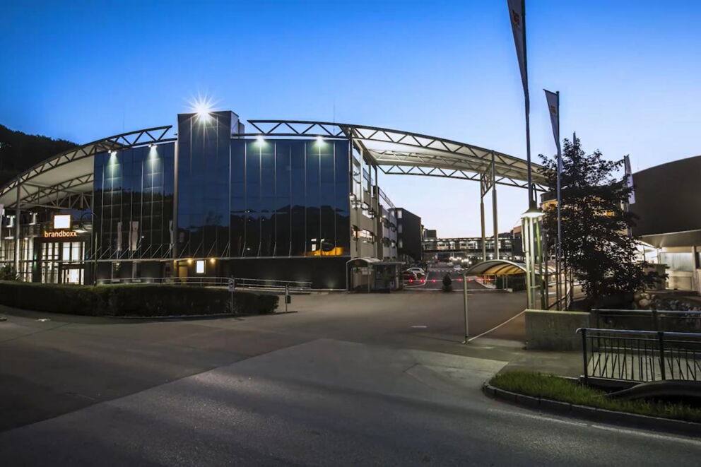 Illuminated modern building complex in front of a blue evening sky with architectural details.