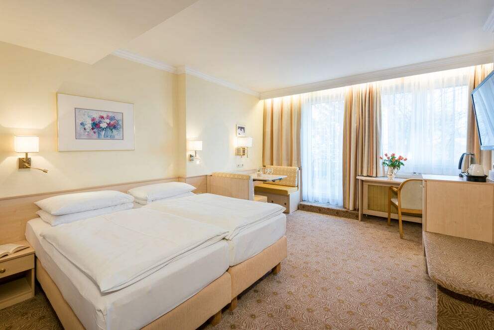 Einladendes Doppelzimmer mit elegantem Dekor und großen Fenstern für viel Licht.