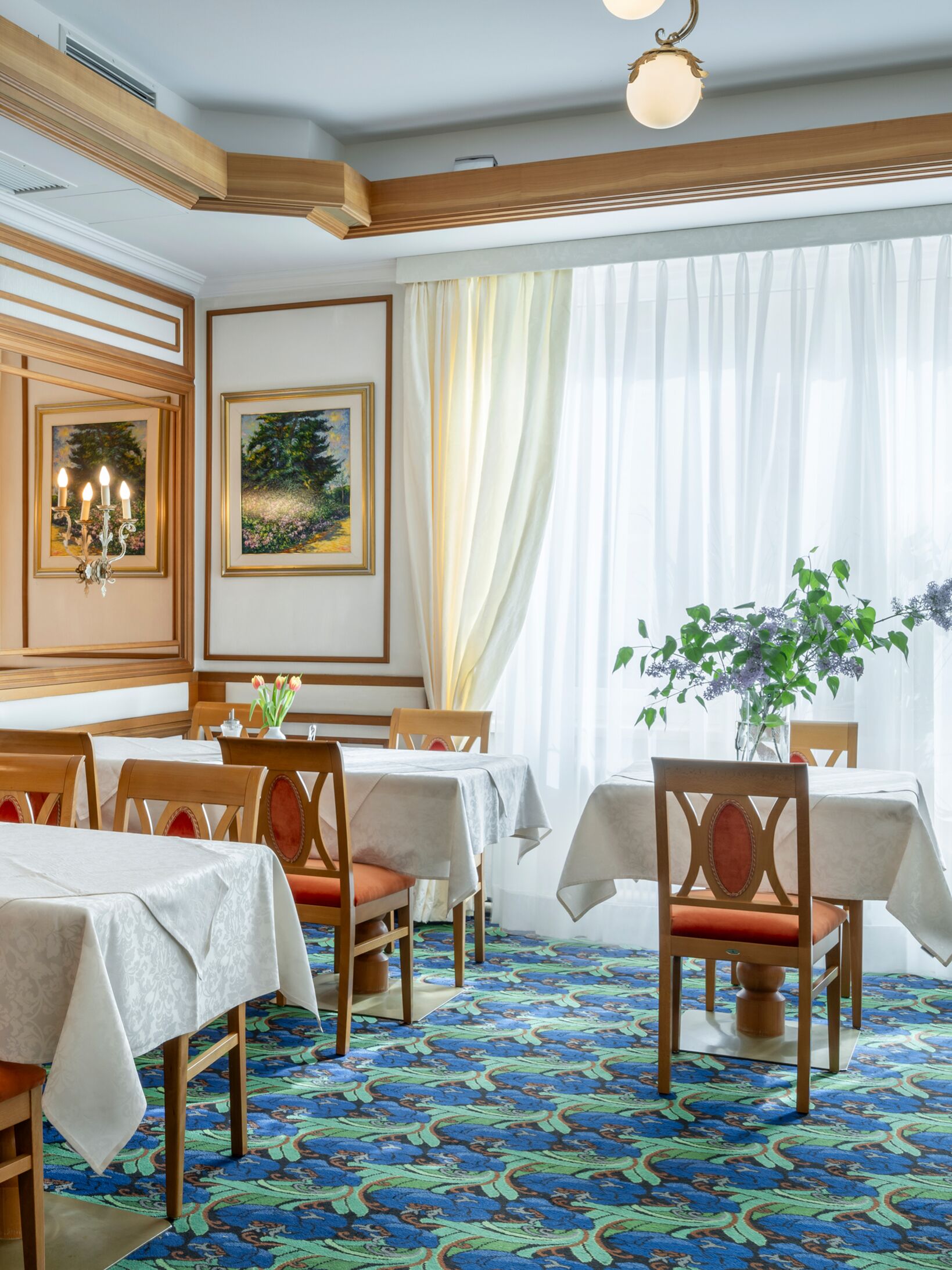 Bright breakfast room with elegant wooden accents and fresh flowers on the tables.