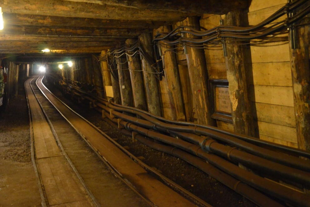 An old gallery with logs, cables and rails inside a mine.