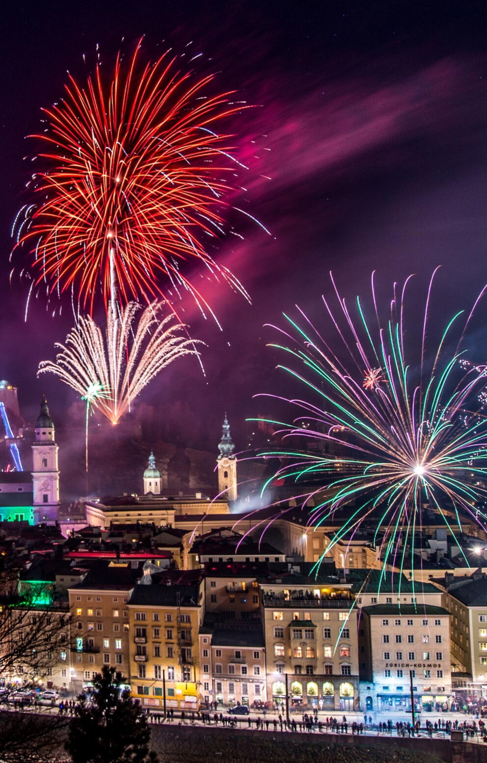 Feuerwerk erhellt den Nachthimmel über der beleuchteten Stadt Salzburg und beeindruckenden Festung.