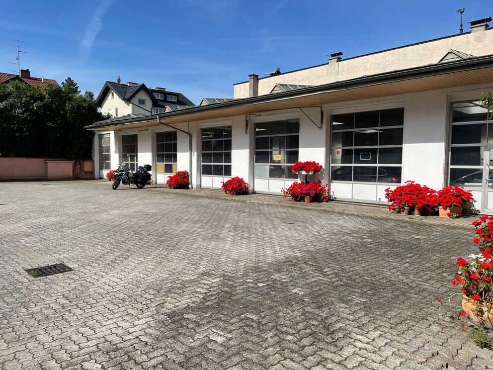 Motorrad parkt vor einem Gebäude mit blühenden roten Blumen im Vordergrund.
