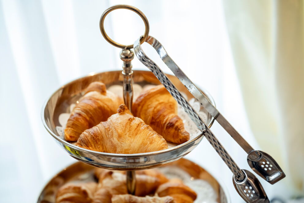 Delicious croissants presented on an elegant etagere with silver tongs.