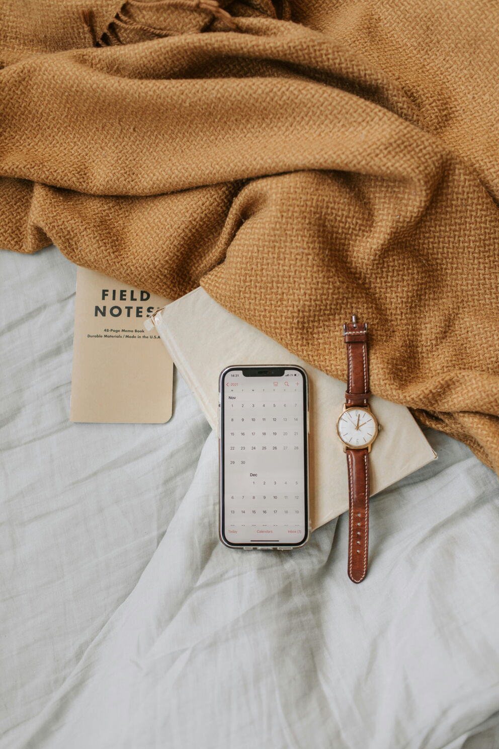 Handy und eine Uhr liegen auf einem Papier im Bett. ©Vlada Karpovich auf Pexels