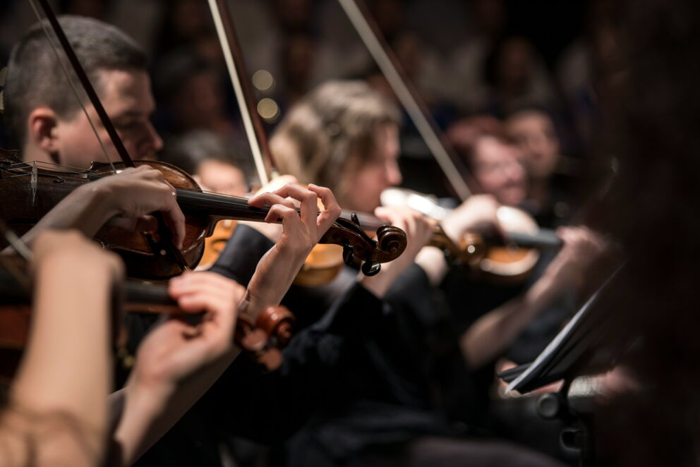 Nahaufnahme von Musikern, die in einem Orchester Violine spielen.