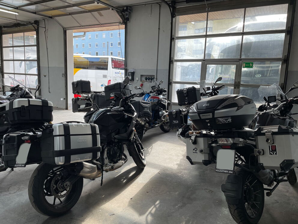 Motorräder in gut beleuchteter Garage mit praktischen Gepäckboxen geparkt.