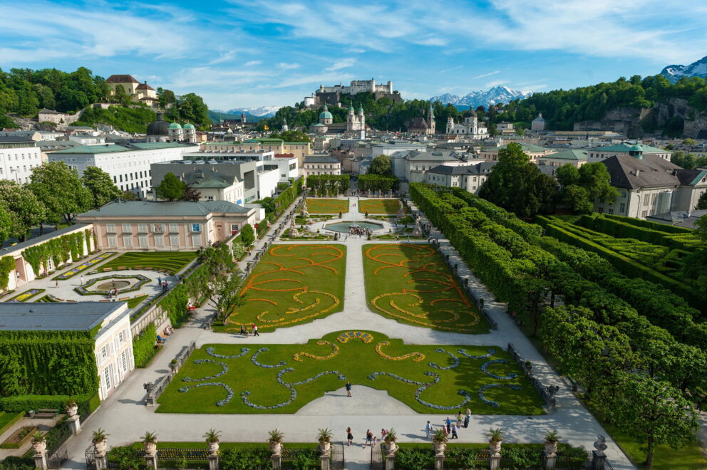 View over magnificent garden in Salzburg with fortress in the background, blue sky.
