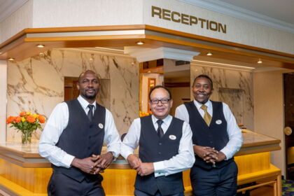 Drei Hotelangestellte in eleganter Uniform an einer stilvollen Rezeption
