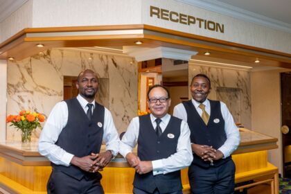 Drei Hotelangestellte in eleganter Uniform an einer stilvollen Rezeption