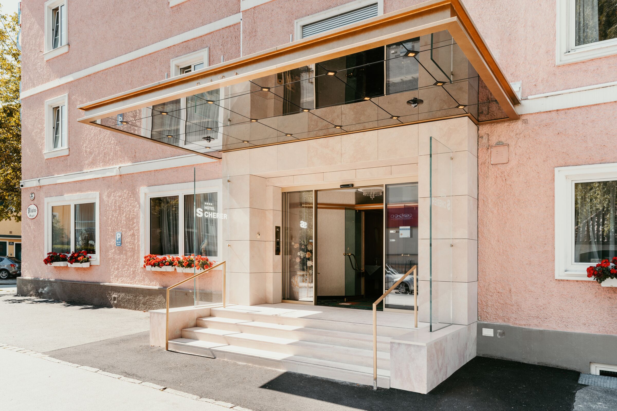 Elegant entrance with flower arrangements and glass details at the Hotel Scherer in Salzburg.