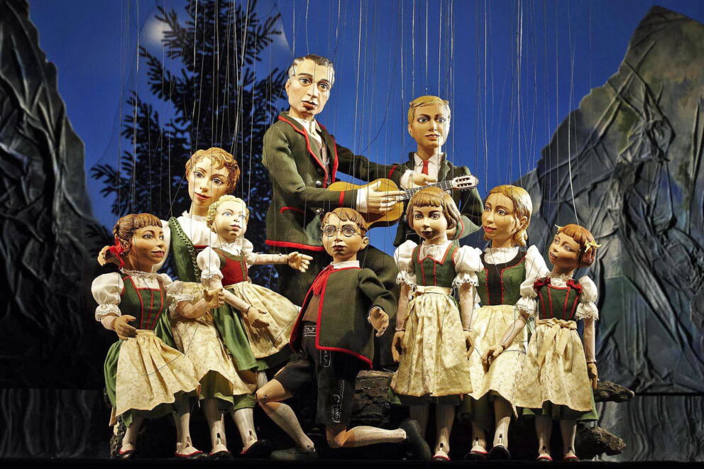 Handmade puppets in traditional dress against a picturesque backdrop of mountains