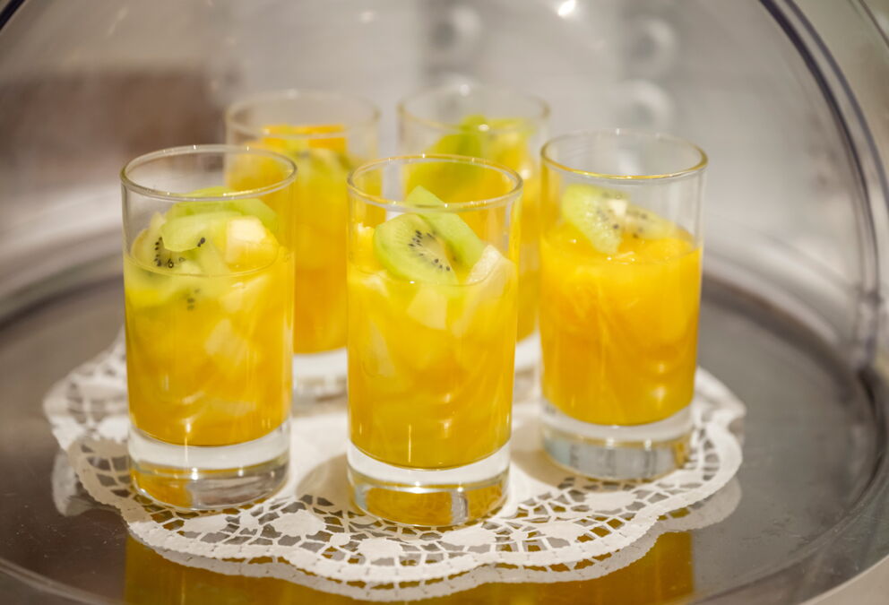 Glasses served with fresh fruit juice and kiwi slices on top.