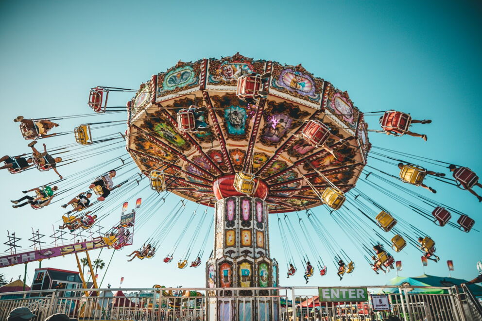 Colorful carousel with swinging seats under a bright blue sky full of joy.