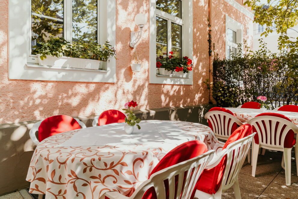 Sonnendurchflutete Terrasse mit blühenden Blumen und gemütlichen Sitzgelegenheiten.