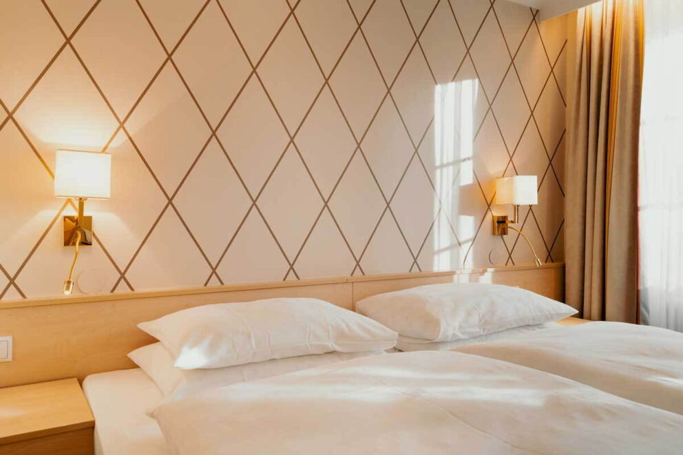 Ein gemütliches Doppelzimmer mit eleganten Wandleuchten und stilvoller Tapete.