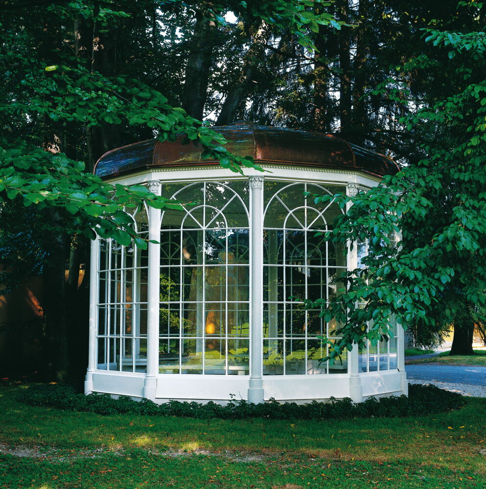 Historic pavilion surrounded by lush greenery and old trees.