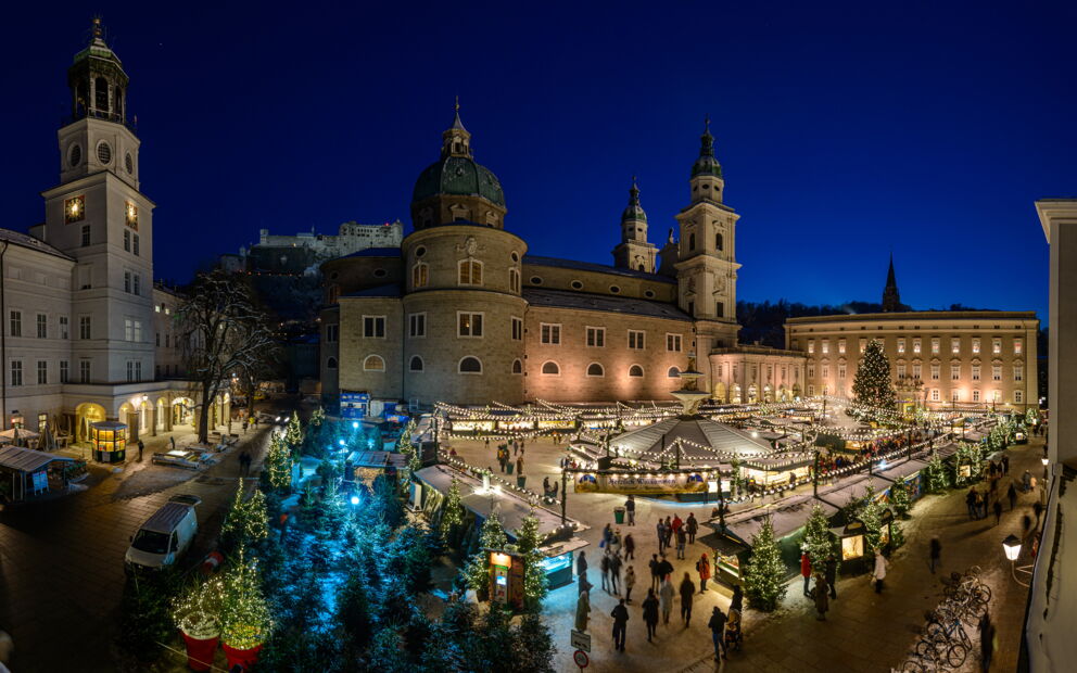 Festlich beleuchteter Weihnachtsmarkt mit historischen Gebäuden bei Nacht in Salzburg.