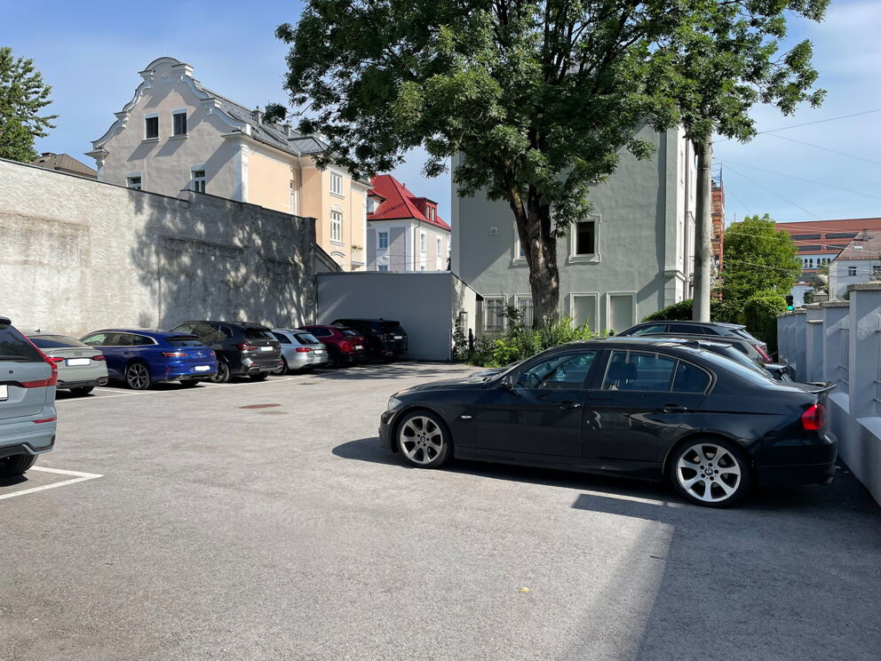 Parkplatz mit mehreren Autos in einer ruhigen städtischen Umgebung nahe historischer Gebäude.