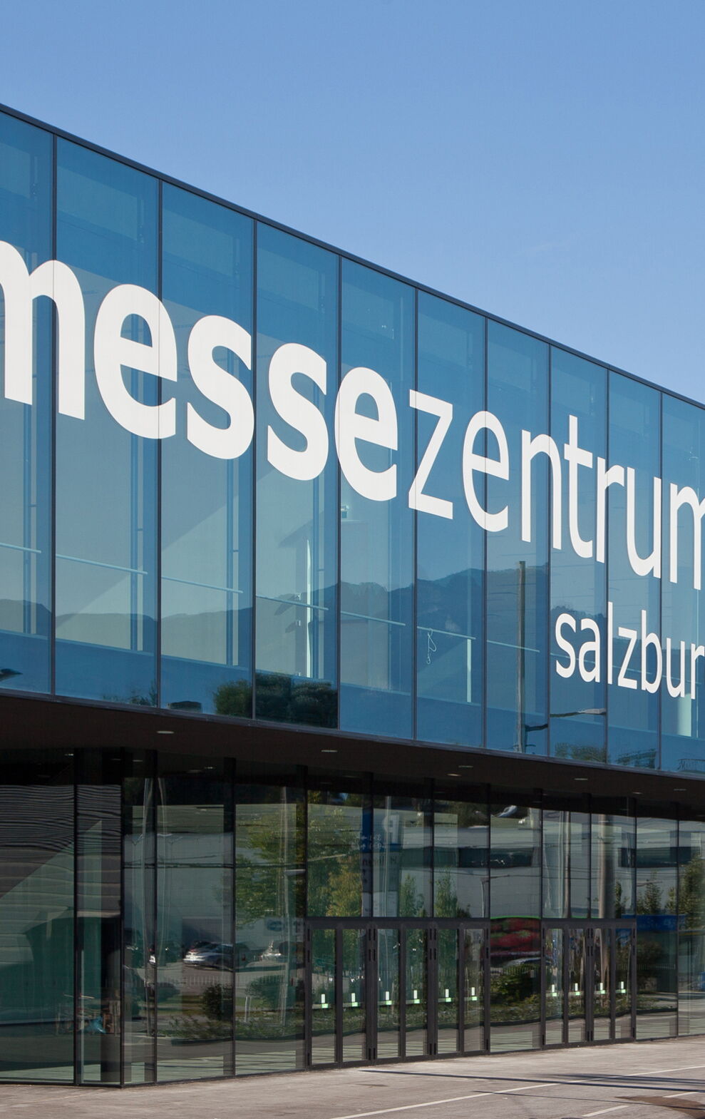 Glasfassade des modernen Messezentrums Salzburg bei blauem Himmel.