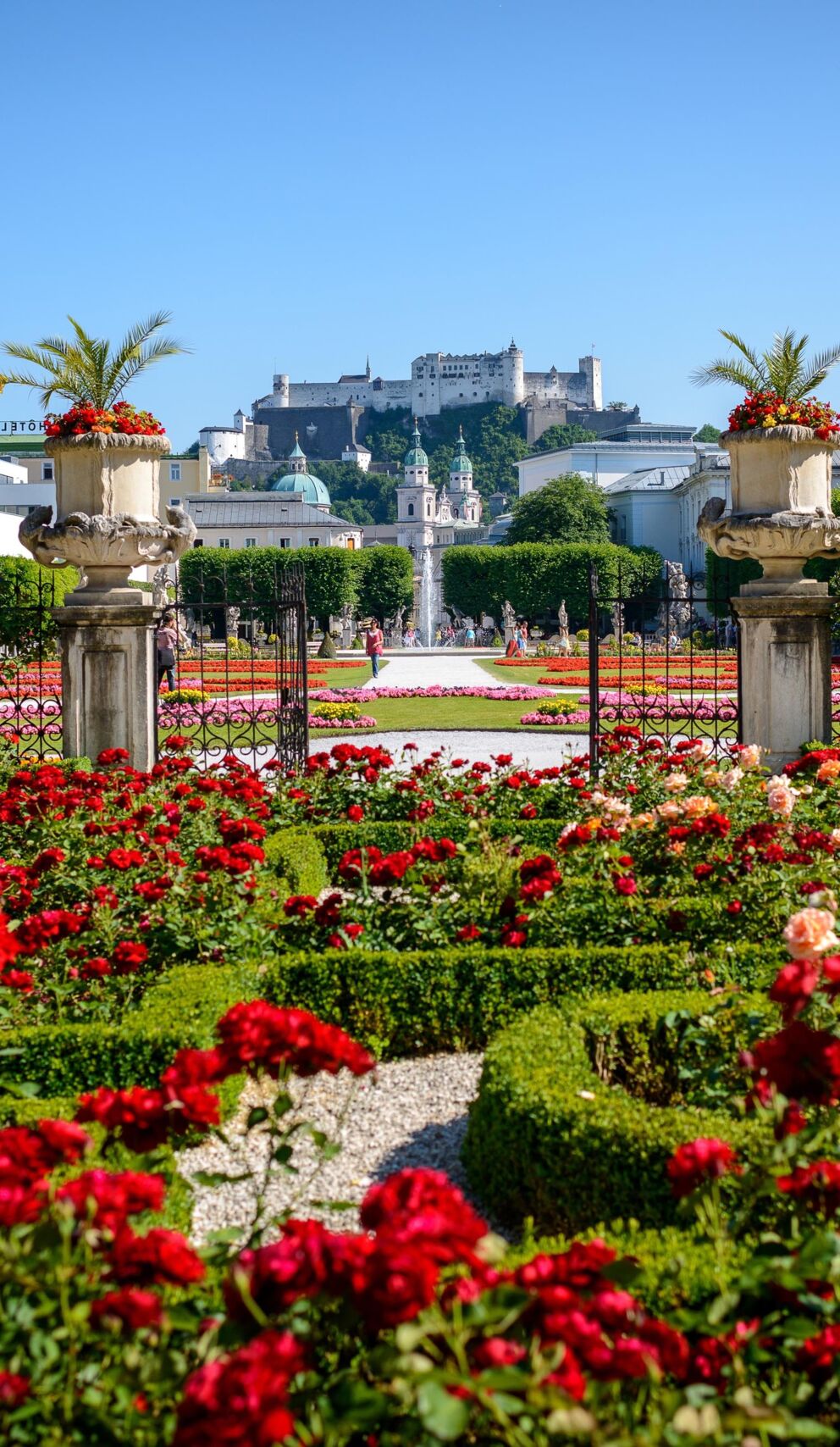 Üppige Blumenbeete vor historischer Kulisse in Salzburg an einem sonnigen Tag.