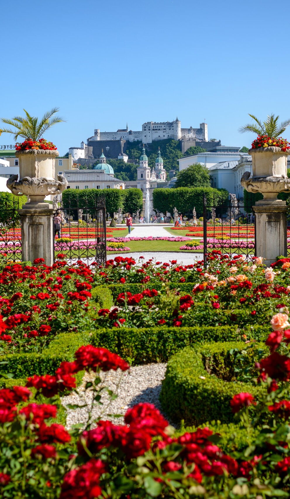Üppige Blumenbeete vor historischer Kulisse in Salzburg an einem sonnigen Tag.