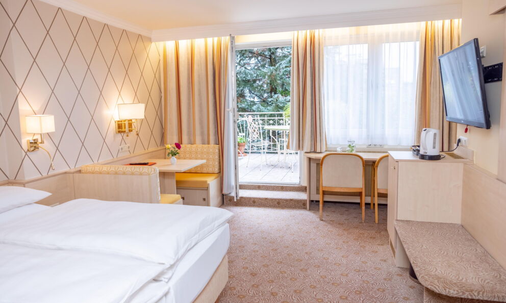 Bright room with comfortable bed, seating area and access to the balcony with garden view.