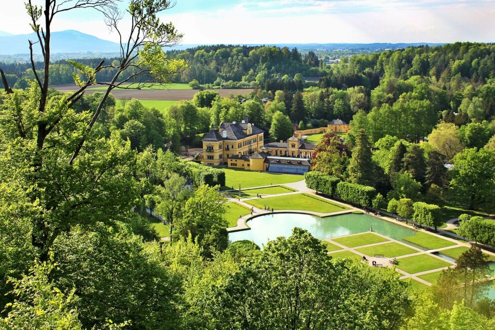 Historisches Schloss mit weitläufigem, grünem Park umgeben von üppiger Natur.