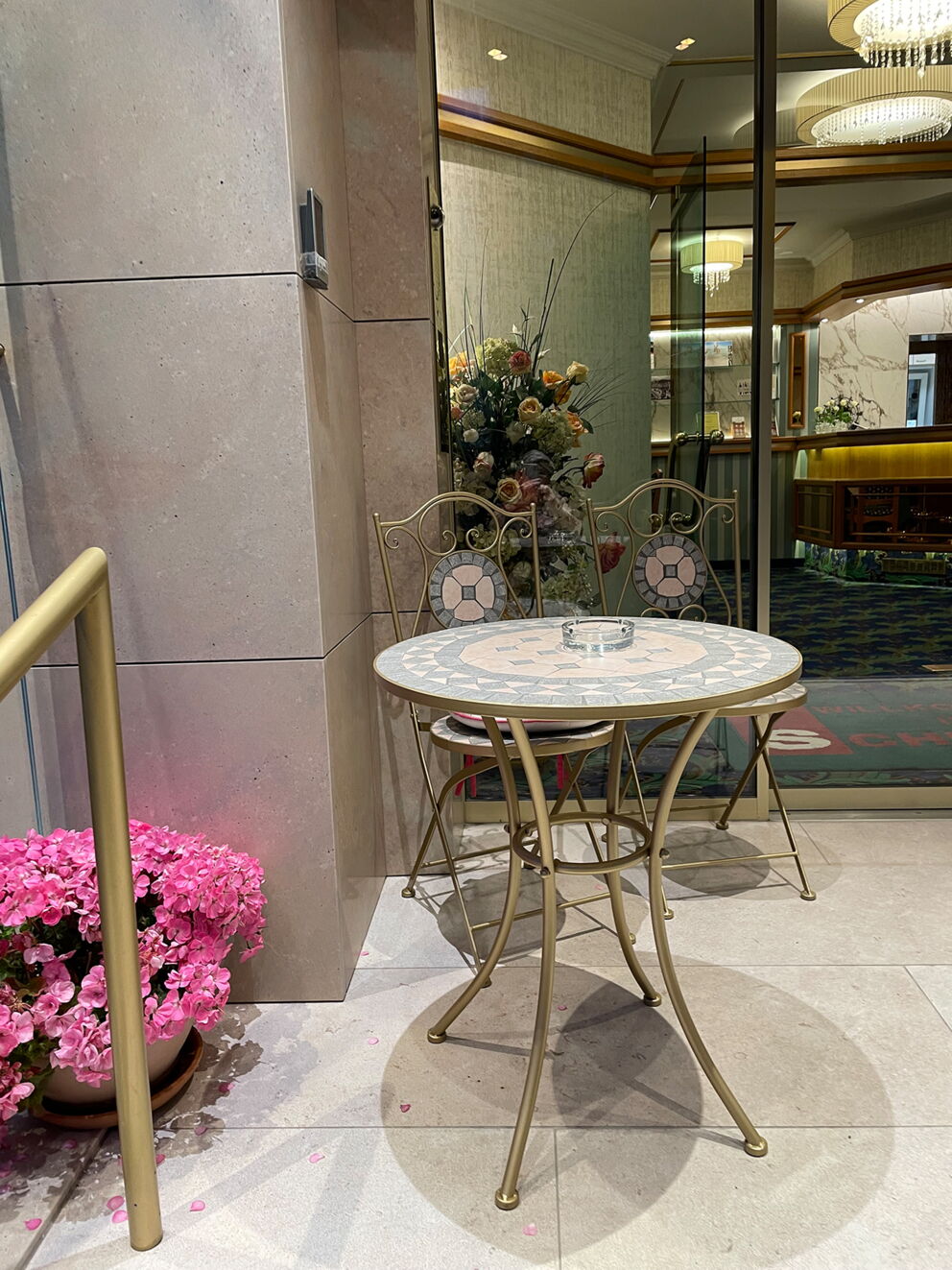 Kleiner Tisch mit Stühlen und Blumenarrangement vor einer Spiegelwand