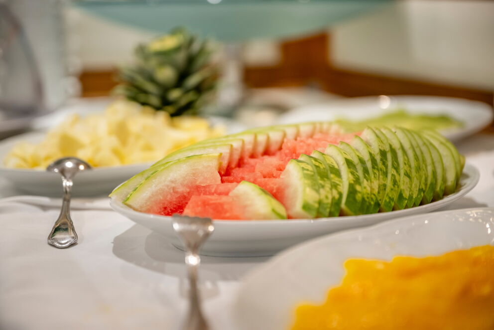 Sorgfältig arrangierte Melonen- und Ananasstücke auf eleganten weißen Tellern präsentiert.