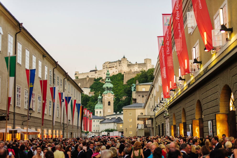 Crowd in front of a historic backdrop with the Festspielhaus and Hohensalzburg Castle.