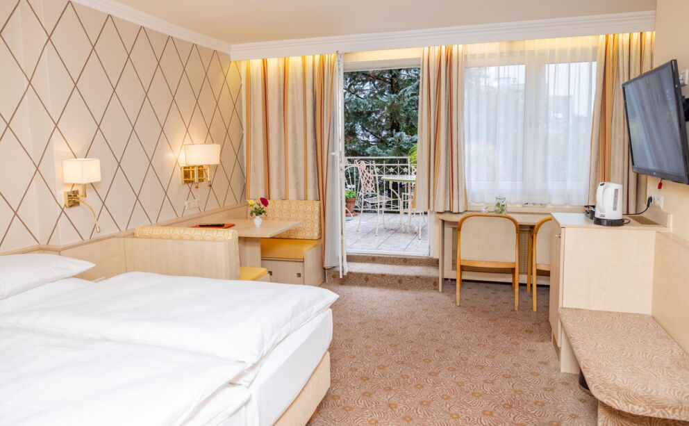 Helles Hotelzimmer mit Balkon, gemütlicher Sitzecke und stilvollem Dekor.