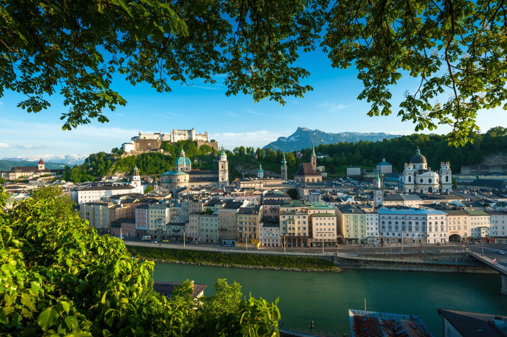 Blick auf Salzburgs Altstadt mit der majestätischen Festung im Hintergrund bei klarem Himmel.