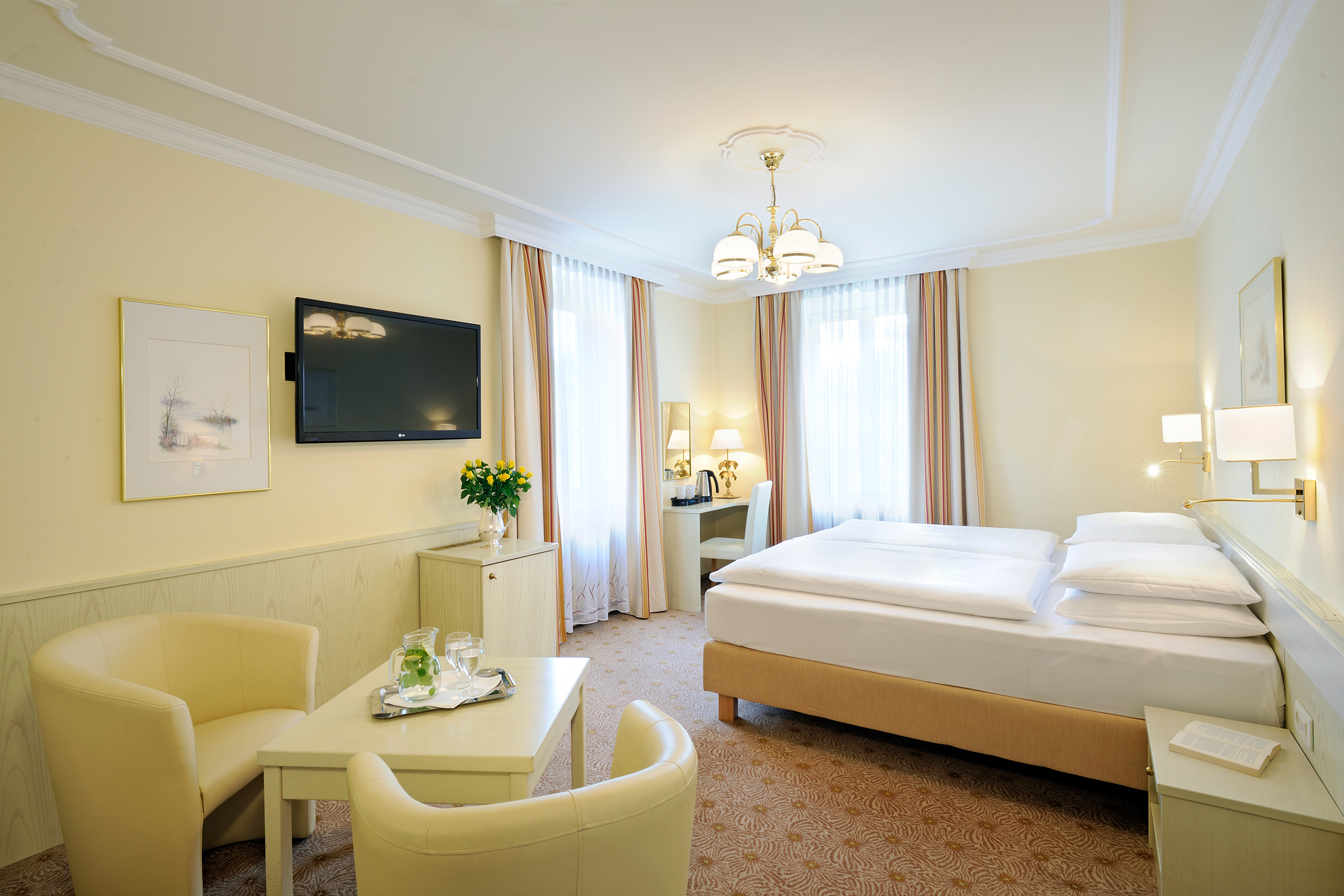 Bright room with double bed, two armchairs, TV and stylish furnishings.
